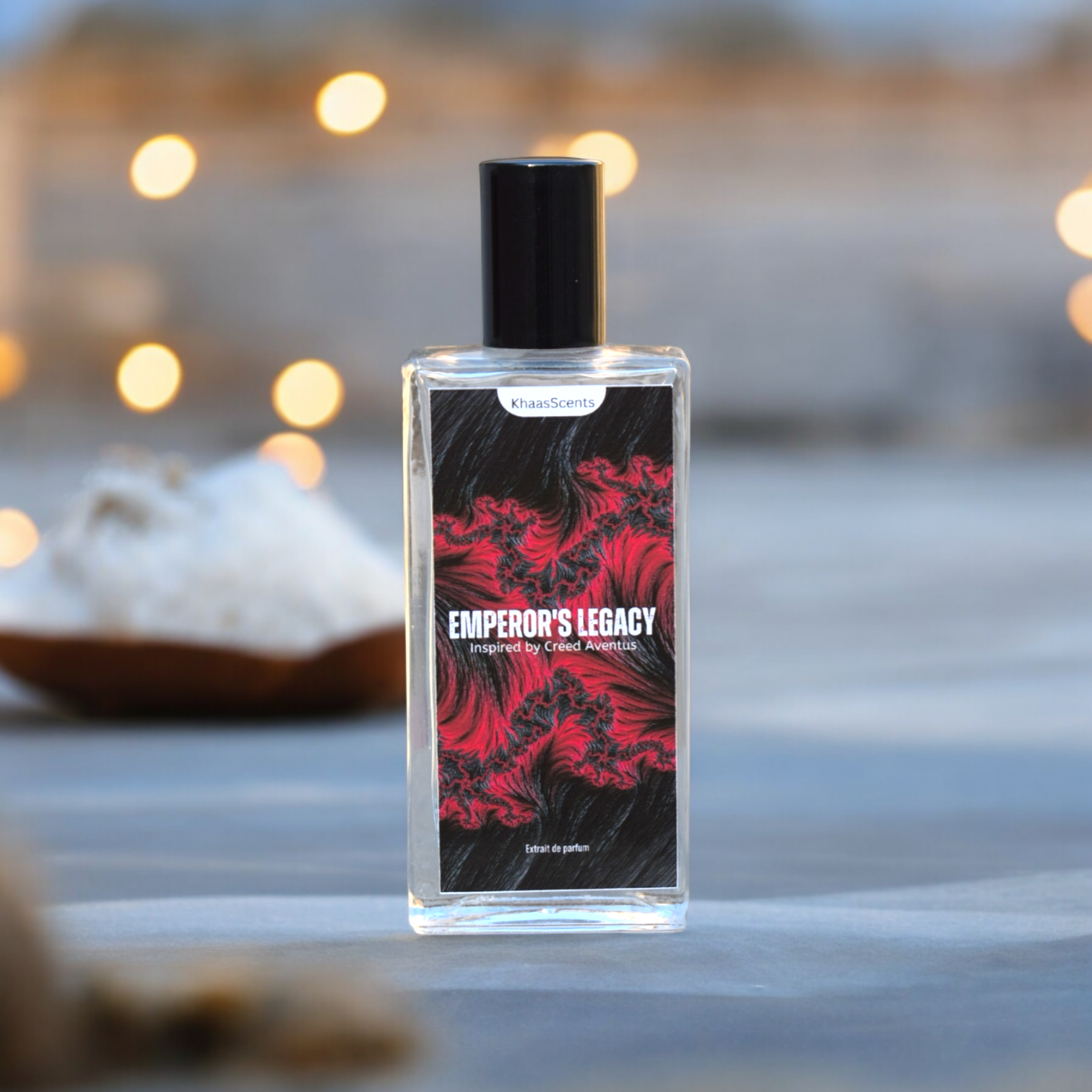 A Perfume named "Emperor Legacy" is placed on the sand at beach with background of Sea and lights