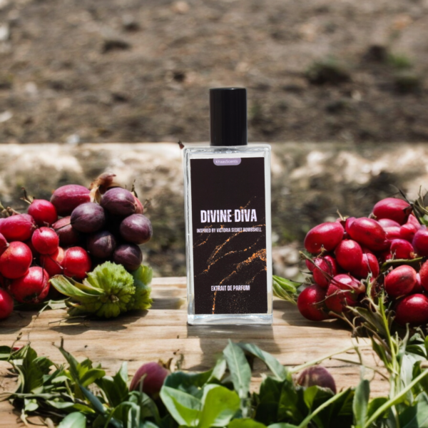 A perfume named "Divine Diva" is placed on a Wooden Tree like stand with background of wall and grapes.